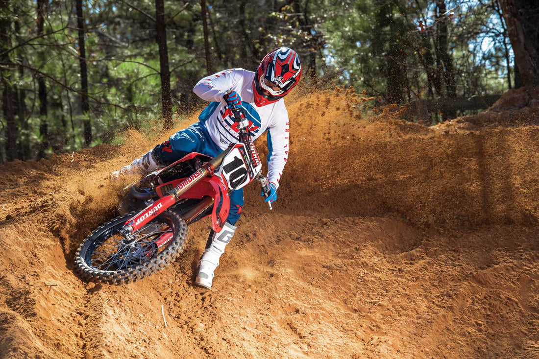 Dirt bike rider on a Honda CRF railing a berm waering Fly Racing Motocross Gear and Gaerne Boots