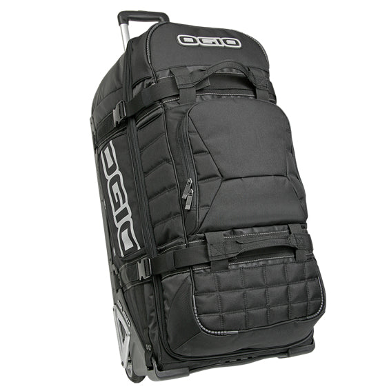 The Ogio RIG 9800 - Black is a durable travel bag featuring multi-use compartments and zipper pockets. It includes a retractable handle for convenient wheeling and padded sections to ensure gear protection. The prominent Ogio logo adorns both the side and the top flap of the bag.