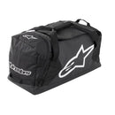 The ALPINESTARS Goanna Duffle Moto Bag is black with bold white logos, carrying handles, a shoulder strap, and a dedicated boots compartment for organized storage.