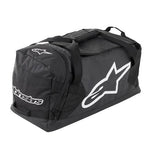 The ALPINESTARS Goanna Duffle Moto Bag is black with bold white logos, carrying handles, a shoulder strap, and a dedicated boots compartment for organized storage.