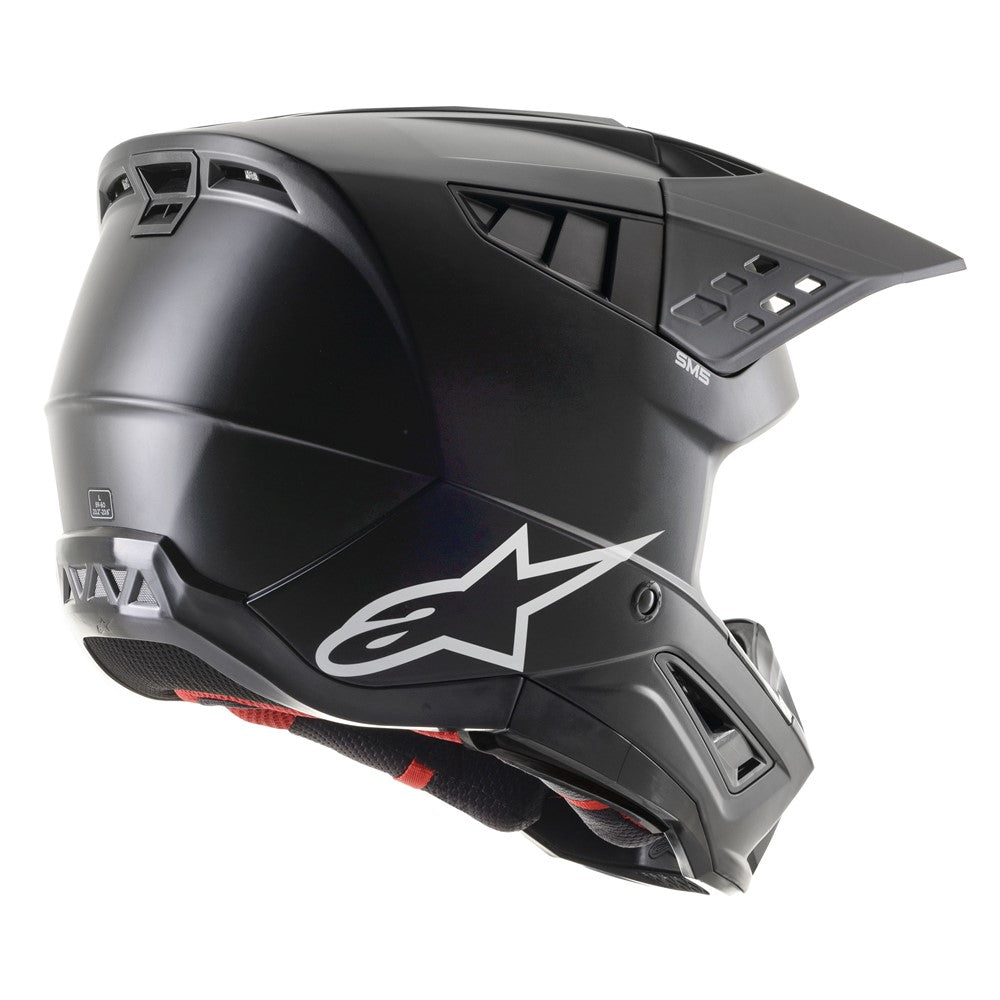 The Alpinestars S-M5 Solid Helmet in Matte Black, offered by Crown Kiwi Enterprises Limited, is a full-face MX helmet made from lightweight thermoplastic. It showcases an angular design with a large visor and red interior padding. The helmet is adorned with a white star logo on the side and includes top ventilation openings for enhanced comfort and impact protection.