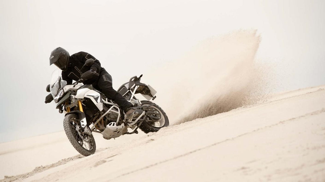 Adventure Rider in the sand dunes, wearing all black adventure gear on a white adventure motorcycle.