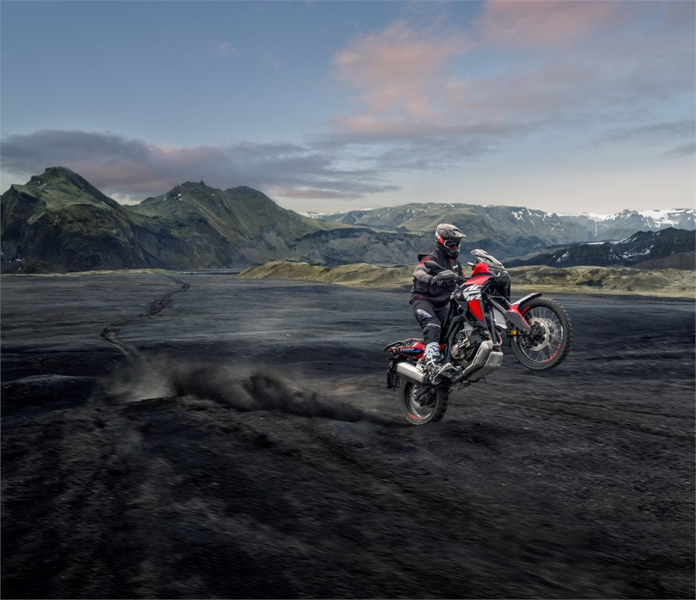 Honda CRF1100 Africa Twin riding through the mountains off-road doing a wheelie