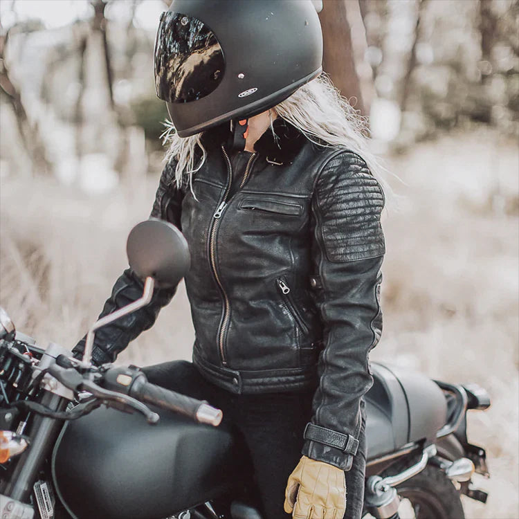 Blonde Lady biker wearing black motorbike helmet, black jacket and black pants on a black motorcycle.