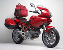 Image shows the Ventura EVO-12 Bike-Pack Kit for Ducati 1000DS Multistrada MTS (03-06) with three labeled components: EVO-12 Pack (black bag), Evo-Rack (metal rack on bike), and L-Bracket (metal bars and screws, “Generic Image”).