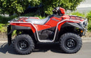 A Ventura-branded Suzuki ATV LT-A 500 AXI is parked, featuring red with black side storage flaps and "Ventura Motorcycle Accessories" text. It includes a rear cargo rack, visible engine components under the seat and sturdy bull-bars for extra protection.