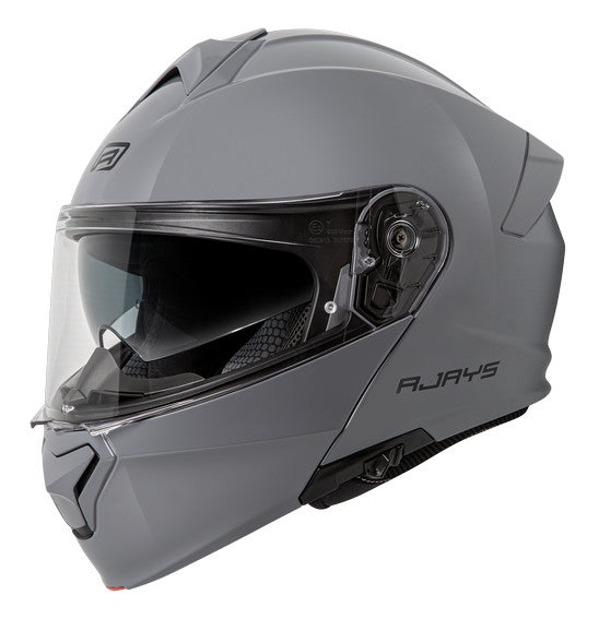 The RJAYS TOURTECH V Helmet in Solid Gloss Grey is a sleek, full-face motorcycle helmet featuring a flip-up front visor. Its aerodynamic shell includes an internal sun visor, a red button for visor release, and a cushioned interior lining. The brand name "RJAYS" is prominently displayed on the side.