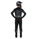 A person is dressed in black and red motocross gear from ONEAL, including a helmet, a long-sleeve top, the O'Neal Youth ELEMENT Voltage V.24 Pant - Black/Red with protective rubber patches, and heavy-duty boots. The individual is standing with their back to the camera and hands on their hips.