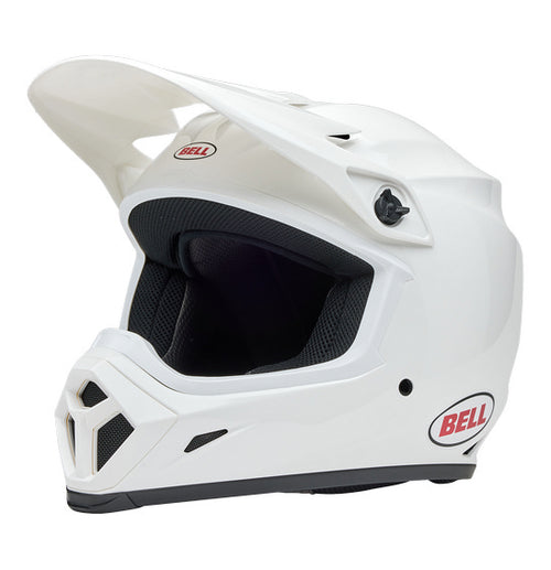 The Bell MX-9 MIPS White full-face helmet features a polycarbonate shell, visor peak, and the Velocity Flow ventilation system for comfort. The BELL logo in red and black adorns the side.