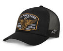 The Heritage Patch Trucker Hat from Crown Kiwi Enterprises Limited is a black mesh hat with a structured crown, featuring an embroidered "Alpinestars Racing Ahead Est. 1963" patch and winged wheel design. It has a snapback for adjustable fit and a small Alpinestars logo on the side.
