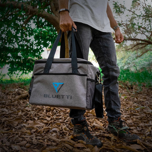 The BLUETTI Carry Bag for EB70/EB55/AC60/AC70 is a gray portable cooler bag with black trim and the "BLUETTI" logo prominently displayed on the front. It is crafted to complement your EB70 and includes a top handle along with an adjustable shoulder strap. The design also incorporates mesh pockets on the sides for additional storage.