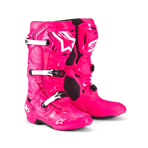 The bright pink Tech-10 MX Boots by Crown Kiwi Enterprises Limited feature black accents, Dynamic Heel Compression Protector, sturdy grip soles, and adjustable straps for a secure fit. The design shows off brand logos and highlights the front and side views.