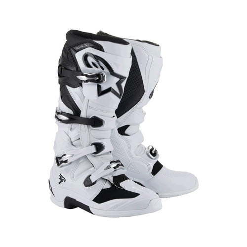 The ALPINESTARS Tech-7 MX Boots in white/black offer adjustable straps and protective features, designed for motocross or off-road use. They feature a sleek, sturdy design, impact resistance, and prominent branding on the top section.