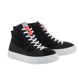The Stella Stated Podium Shoes by Crown Kiwi Enterprises Limited are black high-top skate shoes designed with abrasion-resistant materials, featuring white soles and laces. The tongue includes a red pull tab for easy access. For a stylish display, the left shoe is positioned at an angle, slightly in front of the right.