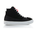 The Stella Stated Podium Shoes by Crown Kiwi Enterprises Limited are black high-top skate shoes designed with abrasion-resistant materials, featuring white soles and laces. The tongue includes a red pull tab for easy access. For a stylish display, the left shoe is positioned at an angle, slightly in front of the right.