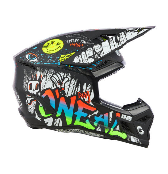 The O'Neal 2025 Youth 3SRS RANCID Helmet - Multi is a black motocross helmet adorned with vivid graffiti-style artwork. The intricate design showcases colorful letters spelling "ONEAL," various doodles, a crown, and multiple expressive faces and symbols. Featuring a Polycarbonate/ABS Shell, the helmet also includes a visor, chin guard for protection, and a washable padded liner for added comfort.