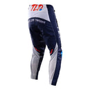 The Troy Lee Designs GP PRO Pant Partical Navy/Orange features navy blue with white and blue graphics, bold thigh lettering, a red accent, durable 600D polyester, reinforced knees, and a black waistband.