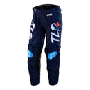 The Troy Lee Designs YOUTH GP PRO PANT PARTICAL NAVY / ORANGE features navy blue with orange accents, white and red details, TLD branding on one leg, heat and abrasion resistant panels, and a belt closure—displayed standing upright.