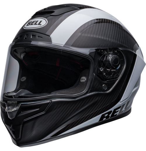 Side view of the Bell RACE STAR DLX FLEX Tantrum 2 Black/White helmet with a clear visor. The helmet boasts a sleek design with aerodynamic contours, Velocity Flow Ventilation, and a textured pattern on the top and sides. A Carbon Fiber Shell ensures durability, while the BELL logo is prominently displayed.