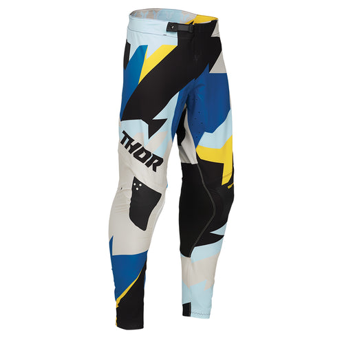 The THOR MX PANTS SPORT BRAVE BLUE are racewear essentials featuring abstract patterns in blue, yellow, black, and white. These colorful motocross pants are designed for unrestricted mobility, with the brand name "THOR" boldly printed on the side to enhance athletic performance.