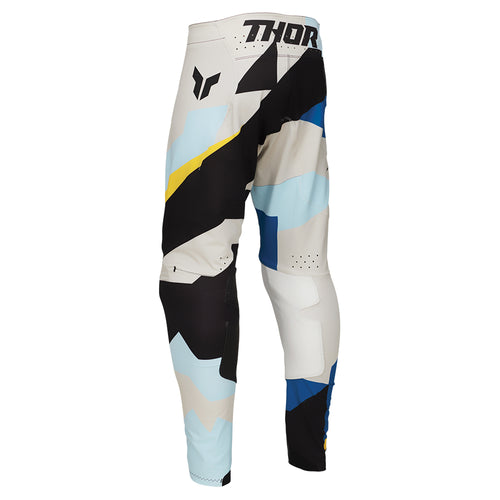 The THOR MX PANTS SPORT BRAVE BLUE are racewear essentials featuring abstract patterns in blue, yellow, black, and white. These colorful motocross pants are designed for unrestricted mobility, with the brand name "THOR" boldly printed on the side to enhance athletic performance.