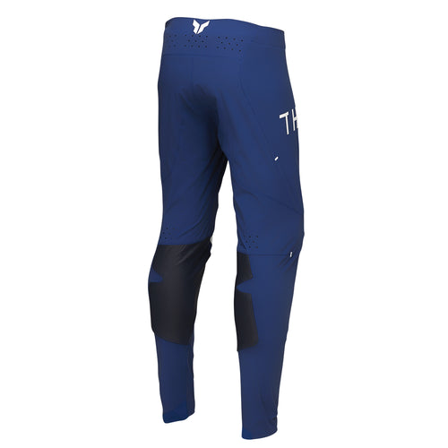 The THOR PANTS SPORT STRIKE NAVY, designed by THOR MX, feature a sleek navy design with white and black accents that ensure unrestricted mobility. The brand name "THOR" is prominently displayed on the right thigh in white letters. Crafted for athletic performance, these pants incorporate reinforced knee areas and a secure white buckle at the waist.