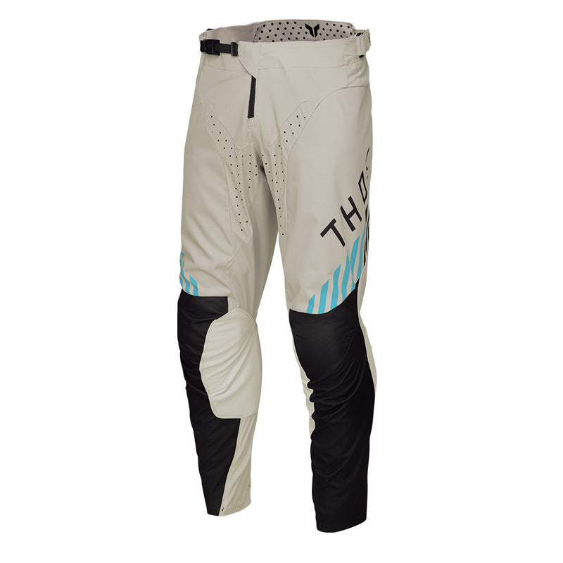 From the LAUNCHMODE collection, the THOR PANTS LAUNCH ZONE SAND by THOR MX are off-road motorcycle pants in beige with black and teal accents. They are crafted from poly stretch fabric for exceptional flexibility and include ventilation holes, a ratchet waist closure system, and reinforced knee areas to ensure both comfort and protection.