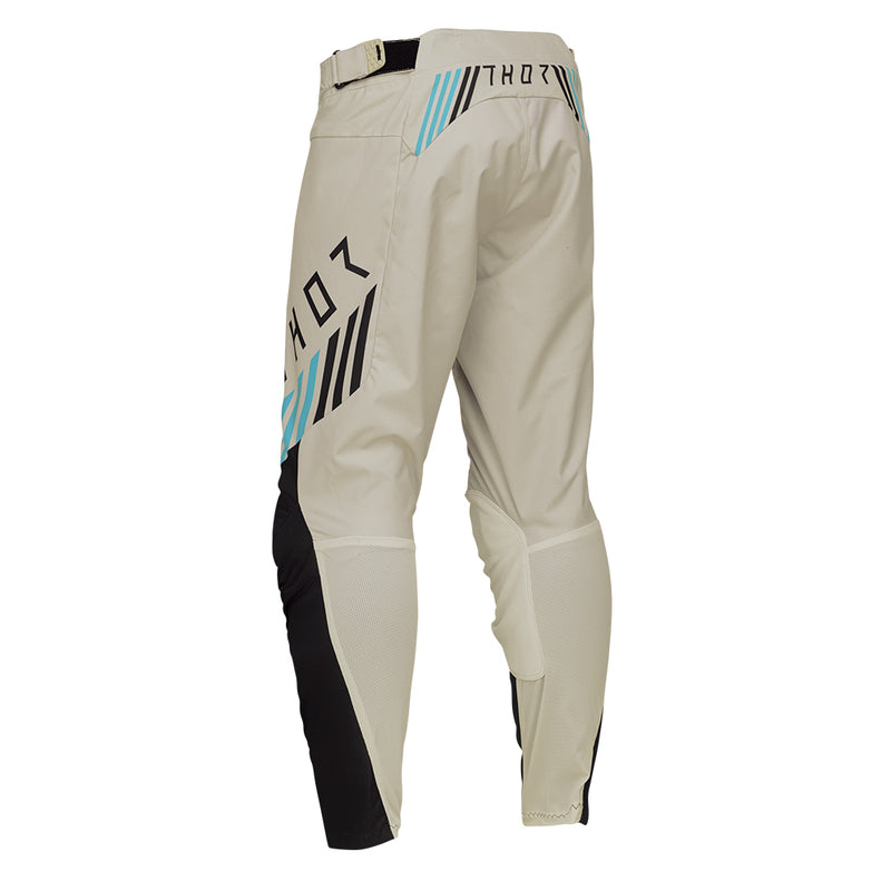 From the LAUNCHMODE collection, the THOR PANTS LAUNCH ZONE SAND by THOR MX are off-road motorcycle pants in beige with black and teal accents. They are crafted from poly stretch fabric for exceptional flexibility and include ventilation holes, a ratchet waist closure system, and reinforced knee areas to ensure both comfort and protection.