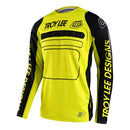 The Troy Lee Designs SE PRO JERSEY DROP IN BLACK / GLO YELLOW is a long-sleeve mountain bike jersey with black sleeves and side panels, Racer Fit for performance, and features bold "Troy Lee Designs" logos in black and yellow.