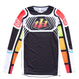 The Troy Lee Designs SE PRO JERSEY WAVEZ BLACK / MULTI is a long-sleeve cycling or motocross jersey with black, white, red, yellow, orange, and green geometric patterns and "td" on the chest. Lightweight fabric ensures comfort.