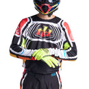 The Troy Lee Designs SE PRO JERSEY WAVEZ BLACK / MULTI is a long-sleeve cycling or motocross jersey with black, white, red, yellow, orange, and green geometric patterns and "td" on the chest. Lightweight fabric ensures comfort.
