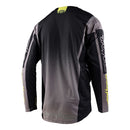 The Troy Lee Designs GP Jersey Icon Black/Gray is a long-sleeved motocross jersey with yellow accents, made from breathable material. It features bold geometric graphics and stylized branding on the chest, sleeves, and hem.