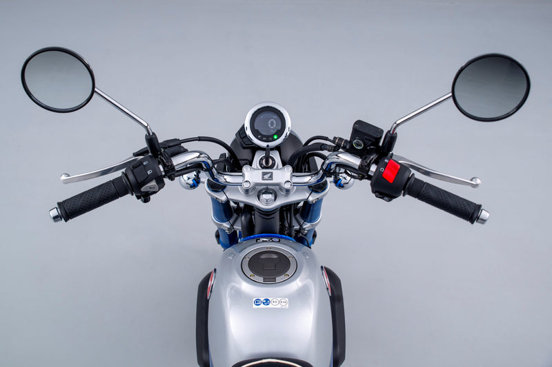 A blue and white retro-style motorcycle with exposed engine and dual rear shocks, positioned on a plain gray background.