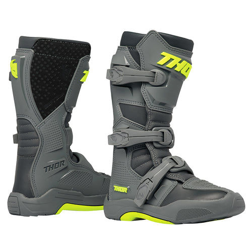 A pair of THOR MX Blitz XR youth boots in gray and charcoal, accented with neon yellow. Made from synthetic materials, they feature multiple adjustable straps and textured soles. One boot is positioned upright while the other is angled to display its back and side profile. Both boots prominently showcase the Thor logo.