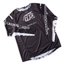 The Troy Lee Designs GP PRO JERSEY BLENDS CAMO BLACK / WHITE is a black long-sleeve motocross top with white branding, "Troy Lee Designs" on the sleeves, "GRAND PRIX" on the front, and ventilated mesh panels for breathability.