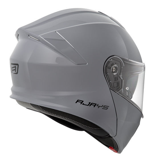 The RJAYS TOURTECH V Helmet in Solid Gloss Grey is a sleek, full-face motorcycle helmet featuring a flip-up front visor. Its aerodynamic shell includes an internal sun visor, a red button for visor release, and a cushioned interior lining. The brand name "RJAYS" is prominently displayed on the side.