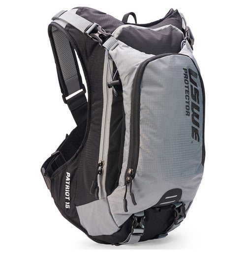 A neatly arranged display of USWE's Patriot 15L MTB Protector Pack highlights its gray backpack with open compartments, black sleek padding, and straps with blue branding. Featuring the CE-certified SAS-TEC protection and an NDM 4-point harness system, it's engineered for high-performance outdoor activities.