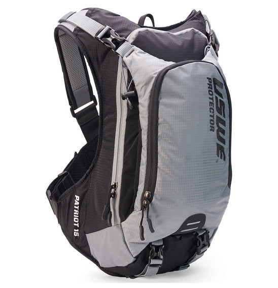A neatly arranged display of USWE's Patriot 15L MTB Protector Pack highlights its gray backpack with open compartments, black sleek padding, and straps with blue branding. Featuring the CE-certified SAS-TEC protection and an NDM 4-point harness system, it's engineered for high-performance outdoor activities.