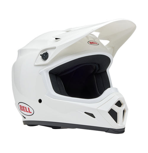 The Bell MX-9 MIPS White full-face helmet features a polycarbonate shell, visor peak, and the Velocity Flow ventilation system for comfort. The BELL logo in red and black adorns the side.