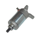 The STARTER MOTOR RICKS MOTORSPORT SUZUKI by RICK'S is a cylindrical electric device with a metallic finish, featuring mounting brackets on both ends and a protruding black shaft. The motor is primarily silver with some weathered or polished texture, and there is a brass screw visible near the center. It comes with a one-year product warranty.