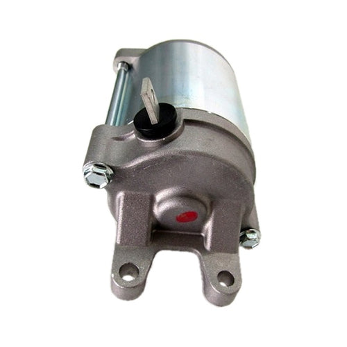 The STARTER MOTOR RICKS MOTORSPORT SUZUKI by RICK'S is a cylindrical electric device with a metallic finish, featuring mounting brackets on both ends and a protruding black shaft. The motor is primarily silver with some weathered or polished texture, and there is a brass screw visible near the center. It comes with a one-year product warranty.