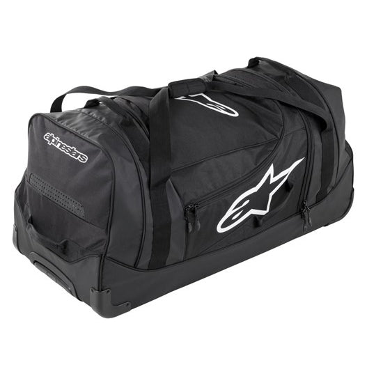 The ALPINESTARS Komodo Travel Bag Black/White is a large, waterproof tarpaulin duffel with wheels and handles, white logos, multiple zippered compartments, and reinforced corners for extra protection.