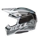 The Bell MOTO-10 SPHERICAL Cortex Gloss Silver/Grey helmet showcases a sleek, modern motocross design with a gray and black swirling pattern. It features angular lines, a visor peak, and incorporates MIPS technology for enhanced safety. The brand name "BELL" is prominently displayed on the side.