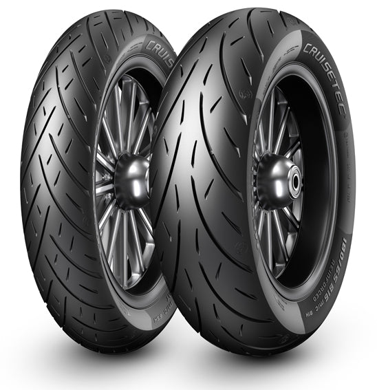 Two black Harley-Davidson motorcycles, sporting robust Metzeler CRUISETEC - Performance Cruiser tires by METZELER, are parked in front of a Harley-Davidson dealership. The image showcases the motorcycles' large rear tires, sleek design, and a hint of urban surroundings with the dealership's branded sign in the background.