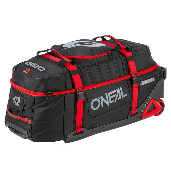 A large, black and red O'NEAL x OGIO RIG 9800 Gear Bag by ONEAL is standing upright. This travel bag is designed with multiple compartments, zippers, and adjustable straps. The SLED system ensures extra durability, while the OGIO logo is prominently displayed on the front alongside the text "ENJOY THE RIDE.