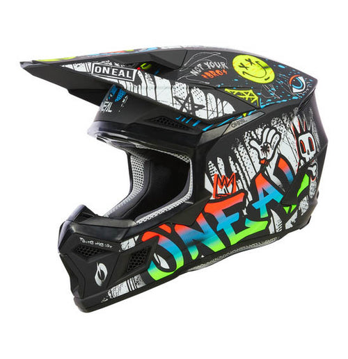 The O'Neal 2025 Youth 3SRS RANCID Helmet - Multi is a black motocross helmet adorned with vivid graffiti-style artwork. The intricate design showcases colorful letters spelling "ONEAL," various doodles, a crown, and multiple expressive faces and symbols. Featuring a Polycarbonate/ABS Shell, the helmet also includes a visor, chin guard for protection, and a washable padded liner for added comfort.