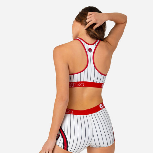 The Ethika Women’s Play Ball Sports Bra from Ethika features black vertical stripes on a white background, crafted from Performance Subzero Fabric. It includes red details on the straps and hem, with "Ethika" written in red cursive text across the chest. The number "01" and the words "FAMILIE" and "ethika" are also displayed on it.