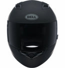 A Bell QUALIFIER Matte Black full-face motorcycle helmet is shown from a side angle, featuring an aerodynamic design with a smooth matte finish and a clear visor. The helmet includes a top vent for airflow, the "Bell" logo on the side, and Multi-Density EPS Liner for enhanced safety.