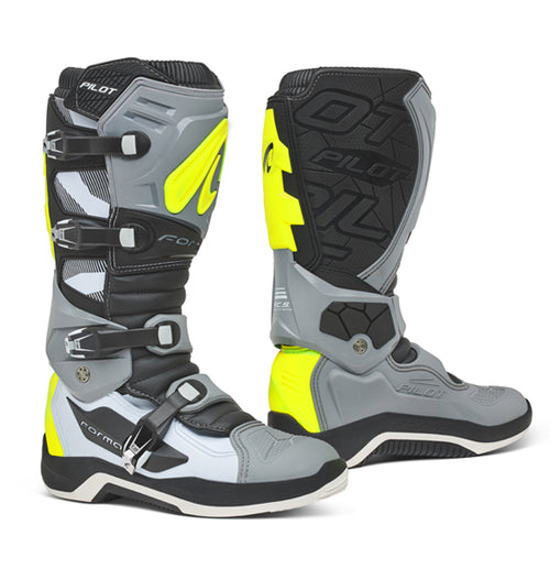 A pair of Forma Pilot - MX motocross boots in black and white, featuring multiple buckles and protective padding. These boots, crafted with a synthetic material upper, showcase the "FORMA" brand prominently on the shin guards and side areas. They boast a sturdy, reinforced design with textured soles for enhanced grip and durability.