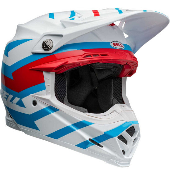 The Bell MOTO-9S FLEX Banshee Gloss White/Red is a safety-focused, full-face motocross helmet adorned with a striking blue, red, and white geometric design. It features a visor, multiple ventilation openings, and the brand name "BELL" in blue on the side. The interior padding is visible around the face opening, making it perfect for off-road racing.